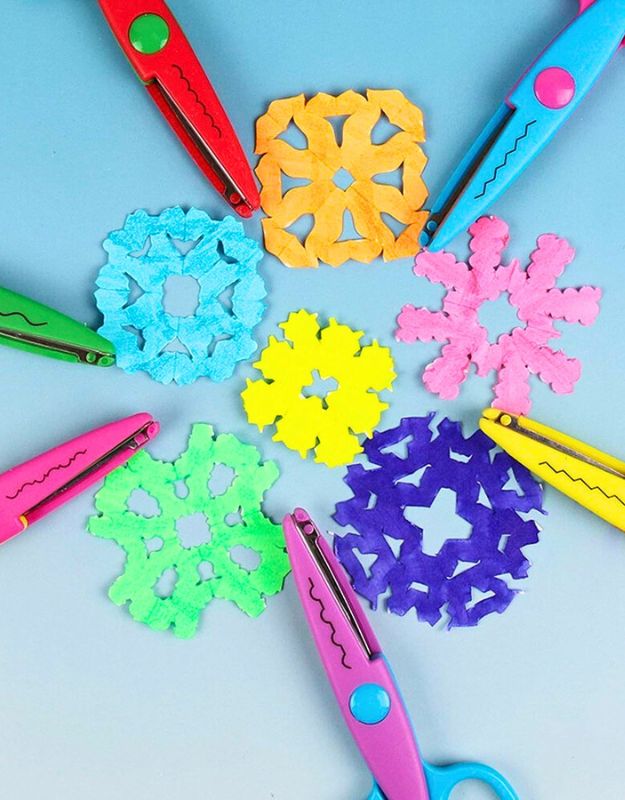 Colorful paper snowflakes arranged in a circle with children's lace scissors around them